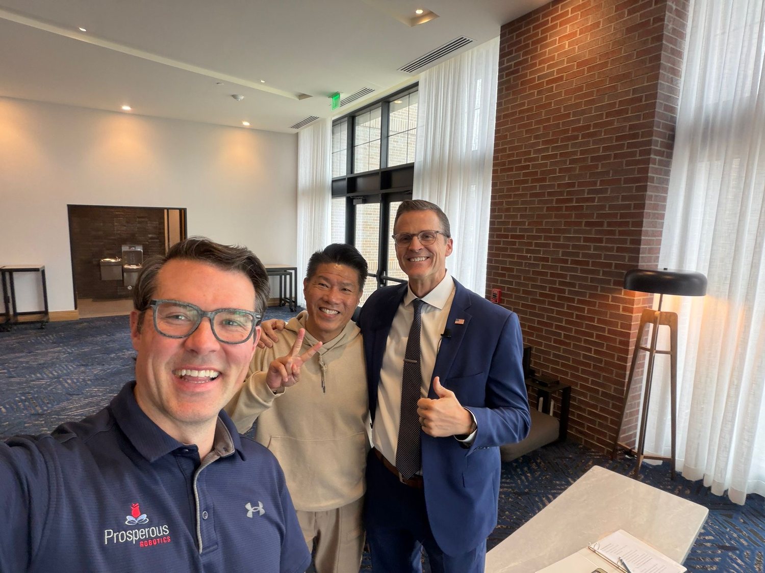 Michael Bankowski, Zen Koh and the former mayor of Sioux Falls standing together in a meeting room, all three smiling at the camera.